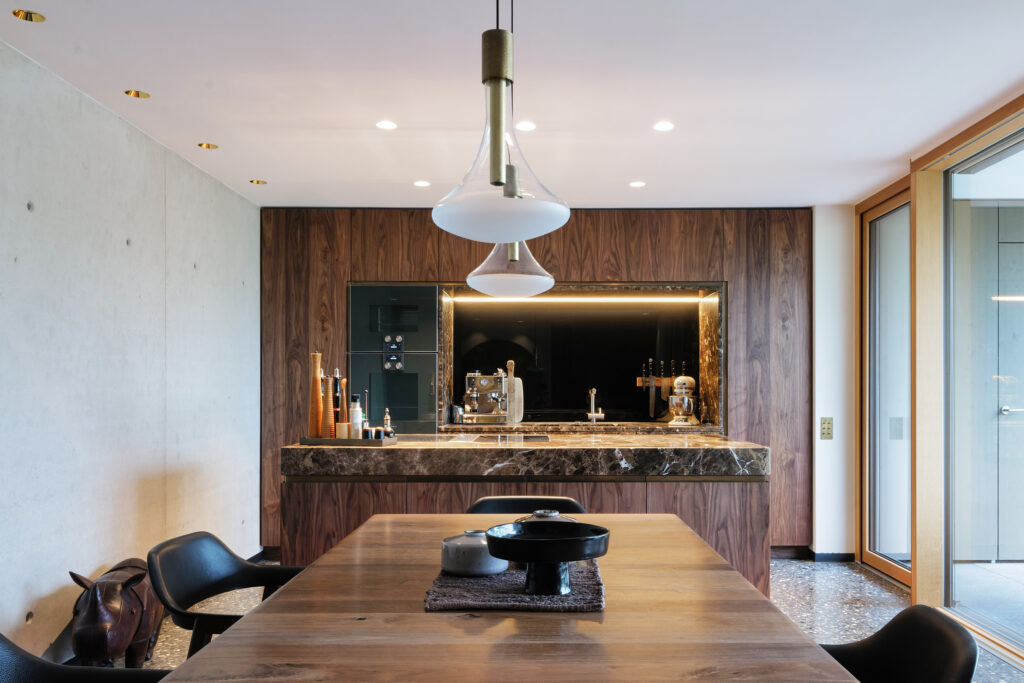 Moderne Küche in Nussbaum geölt, großem Esstisch und zwei Hängelampen über der Tischmitte