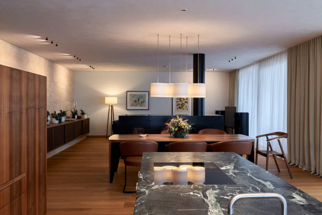 Offener Wohnraum mit Esstisch, Hängelampen, Kücheninsel mit Marmorplatte, Besonderen Leuchten und exklusiver Möblierung
